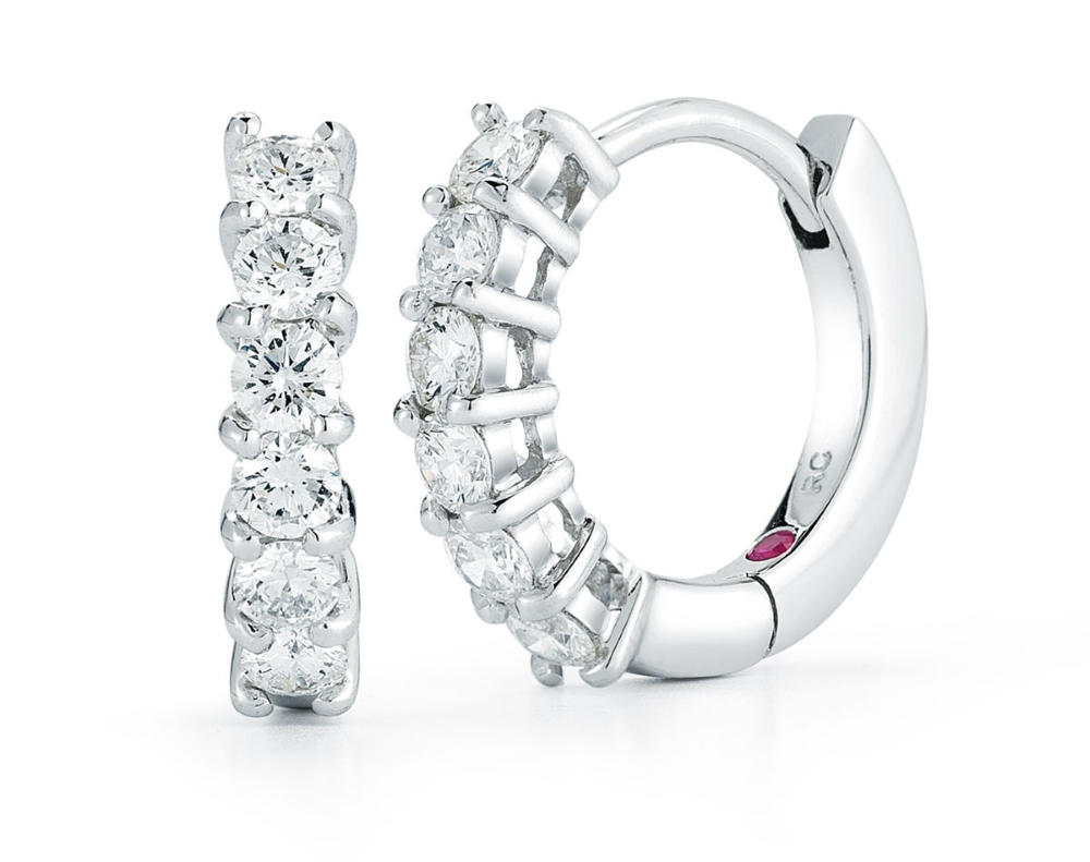 A pair of 18K white gold huggie hoop earrings featuring multiple round diamonds set in a continuous row.