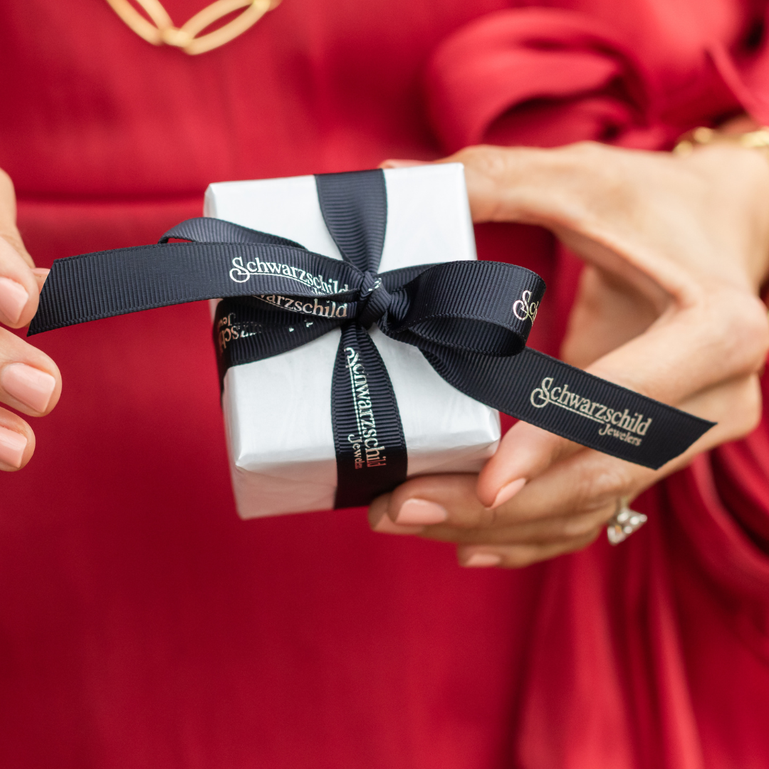 A woman holding a Schwarzschild Jewelers box wrapped with ribbon