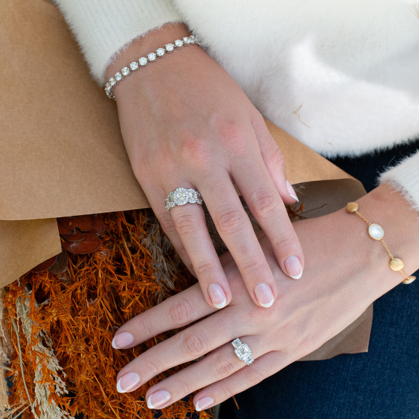 Woman holding a collection of Thanksgiving fall flowers while wearing silver bracelets and engagement and wedding rings