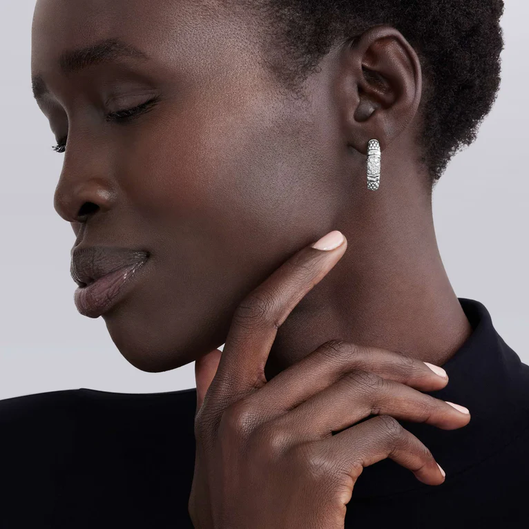 Close-up of a woman wearing a silver hoop earring with a neutral background