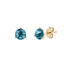A pair of martini stud earrings featuring round london blue topaz stones set in 14K yellow gold with three-pronged settings.