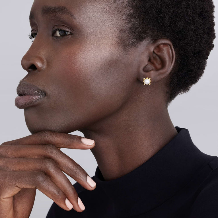 Close-up of a woman wearing a gold earring with a neutral background