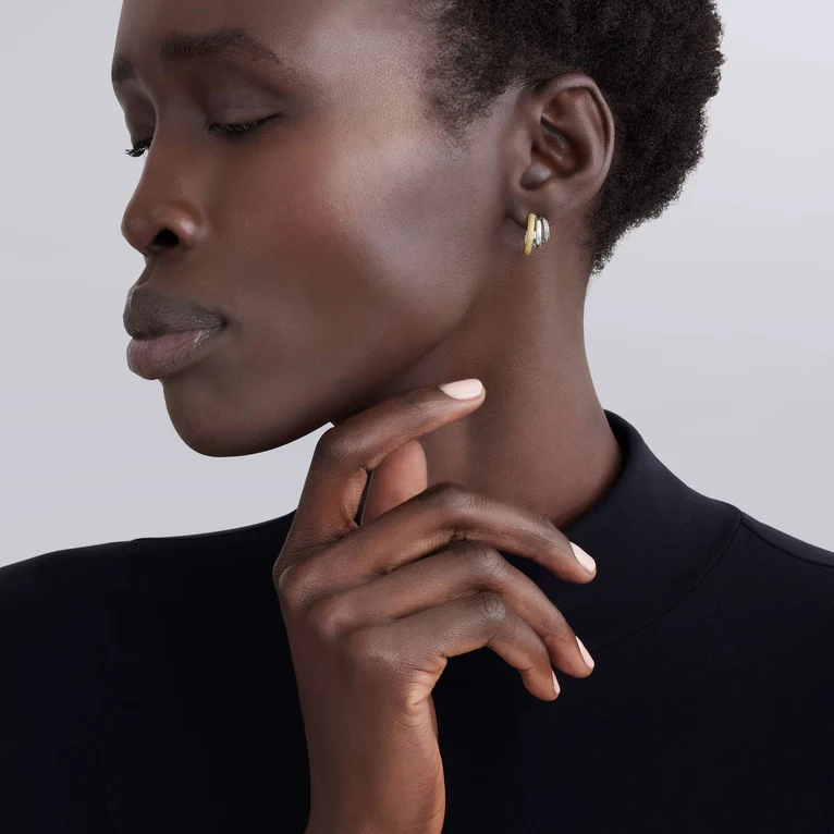 Close-up of a woman wearing gold earrings with a neutral background