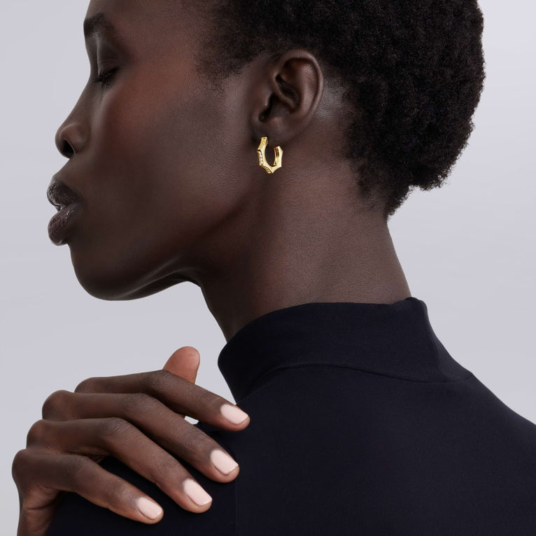 Woman wearing gold hoop earrings with a neutral background