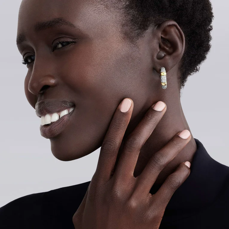 Woman wearing a gold hoop earring with a gray background