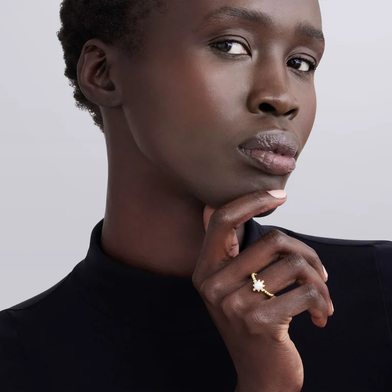 Woman wearing a gold ring on a plain background